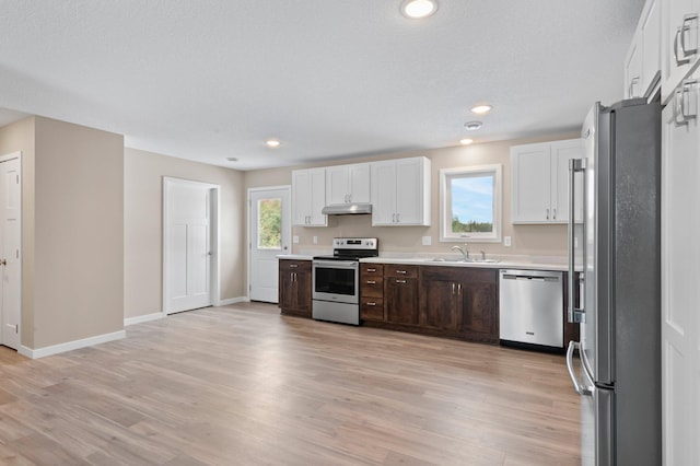 kitchen with dark brown cabinetry, a wealth of natural light, stainless steel appliances, and light wood-type flooring