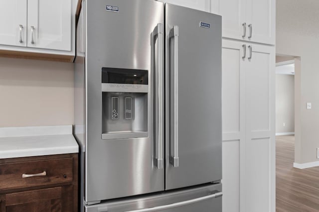 interior details with white cabinetry, stainless steel fridge with ice dispenser, dark brown cabinetry, and light hardwood / wood-style floors