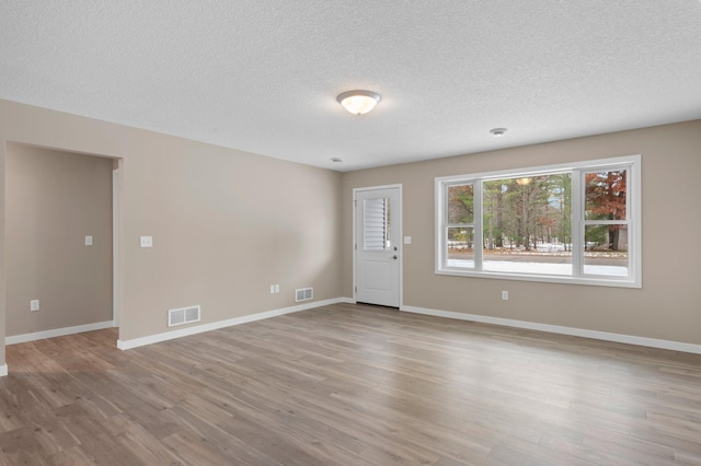 empty room featuring a textured ceiling and light hardwood / wood-style flooring