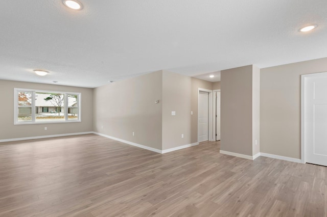 empty room with a textured ceiling and light hardwood / wood-style flooring