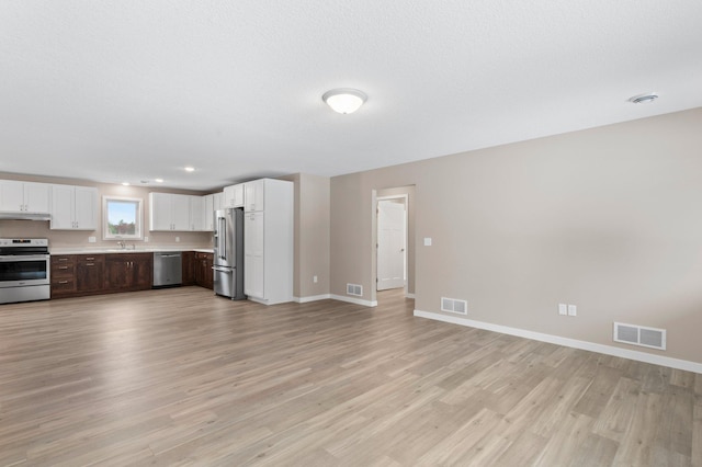 kitchen featuring white cabinets, sink, light hardwood / wood-style flooring, and appliances with stainless steel finishes