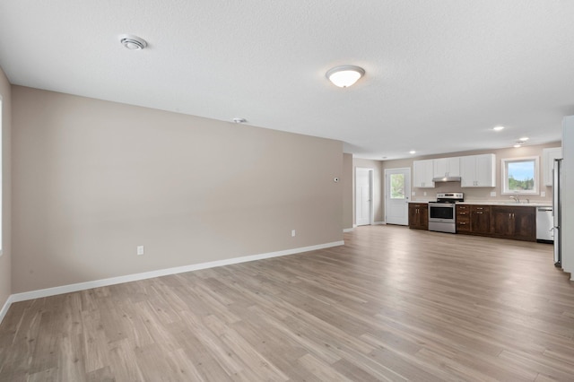 unfurnished living room featuring sink, a textured ceiling, and light hardwood / wood-style flooring