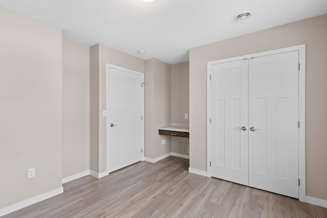 unfurnished bedroom featuring light wood-type flooring, a textured ceiling, and a closet