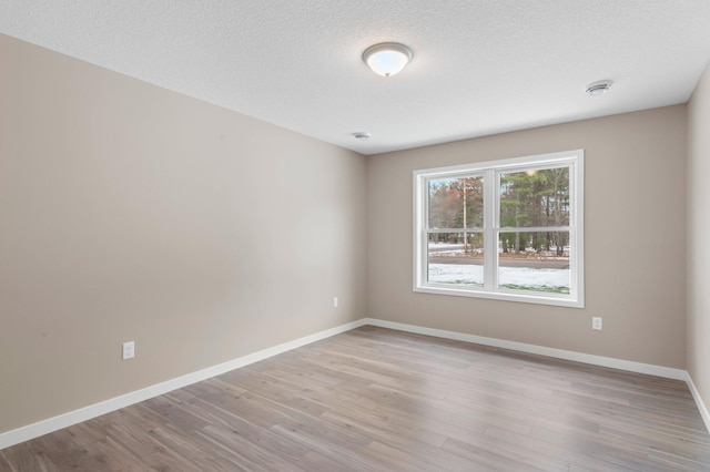 unfurnished room with light wood-type flooring and a textured ceiling