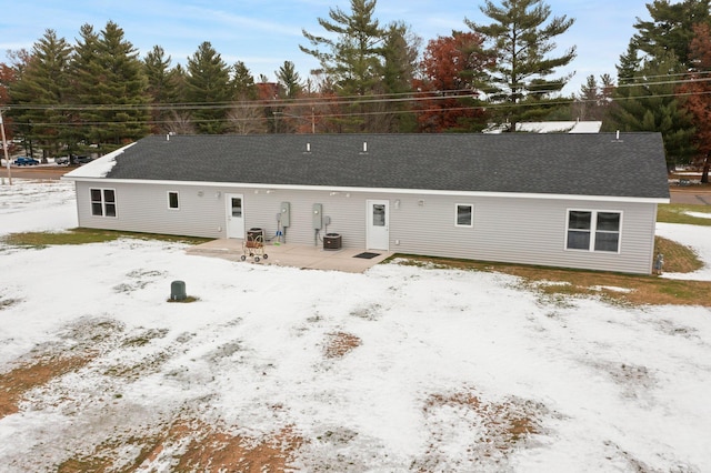 snow covered property with central air condition unit and a patio area