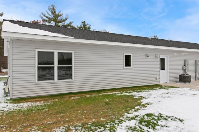 snow covered rear of property featuring a yard