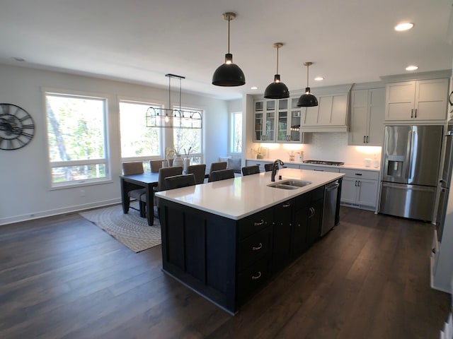 kitchen featuring white cabinetry, dark hardwood / wood-style flooring, stainless steel appliances, a kitchen island with sink, and sink