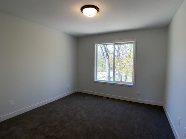 spare room featuring dark colored carpet