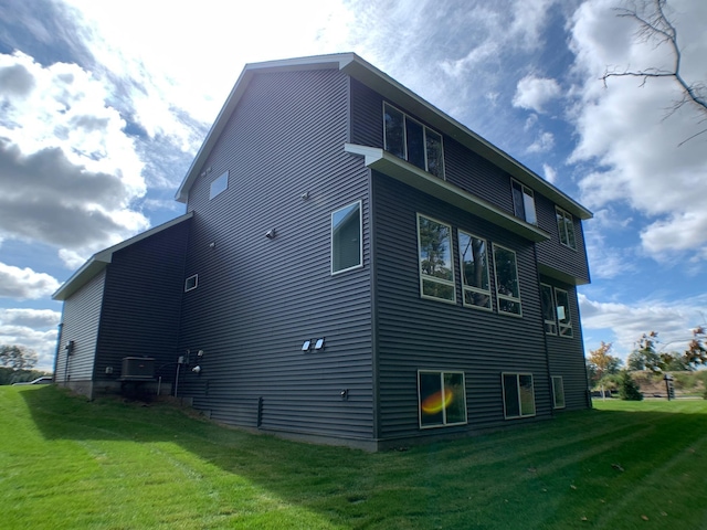 back of property with central AC unit and a yard