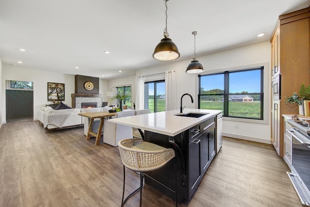 kitchen featuring decorative light fixtures, light hardwood / wood-style flooring, sink, and a wealth of natural light