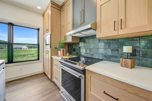 kitchen featuring light brown cabinets, backsplash, stainless steel appliances, and light wood-type flooring