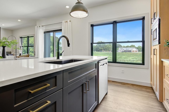 kitchen featuring light hardwood / wood-style floors, decorative light fixtures, appliances with stainless steel finishes, and sink