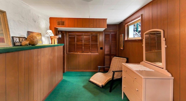 sitting room with wood walls and dark carpet