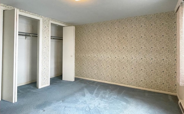 unfurnished bedroom with multiple closets and dark colored carpet