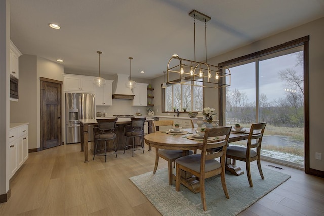 dining room with sink, light hardwood / wood-style flooring, and a chandelier