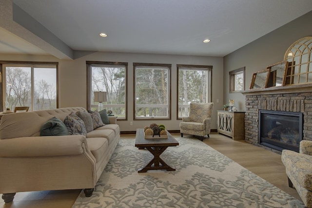 living room with a brick fireplace, light hardwood / wood-style flooring, and a healthy amount of sunlight