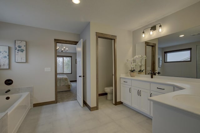 bathroom with a healthy amount of sunlight, a tub, vanity, and toilet