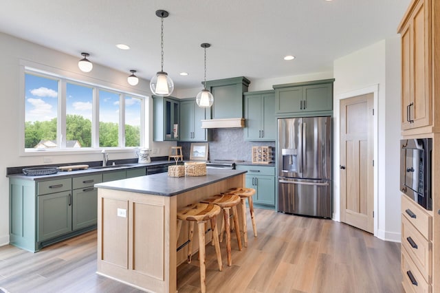 kitchen with a kitchen island, sink, stainless steel fridge, light wood-type flooring, and premium range hood