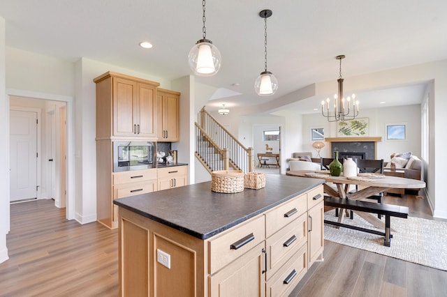 kitchen featuring stainless steel microwave, light brown cabinetry, dark hardwood / wood-style floors, pendant lighting, and a center island