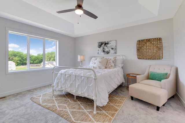 carpeted bedroom featuring a raised ceiling and ceiling fan