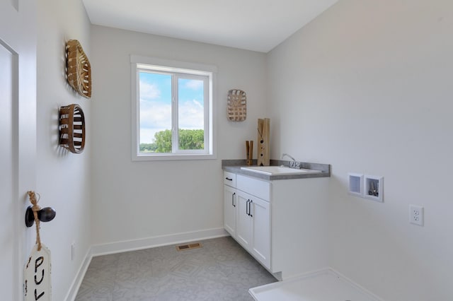 clothes washing area featuring hookup for a washing machine, light tile patterned floors, cabinets, and sink