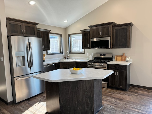 kitchen with stainless steel appliances, sink, a kitchen island, dark hardwood / wood-style flooring, and vaulted ceiling