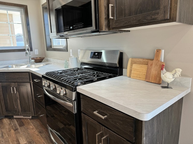 kitchen with dark brown cabinets, stainless steel appliances, dark wood-type flooring, and sink