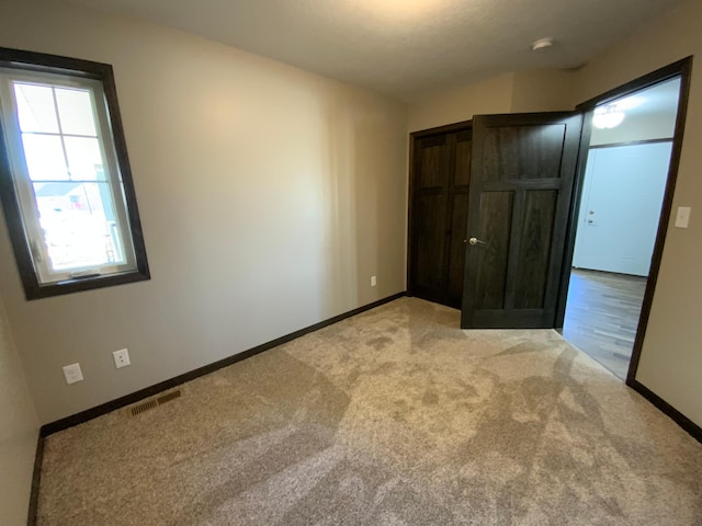 unfurnished bedroom featuring light carpet and a closet