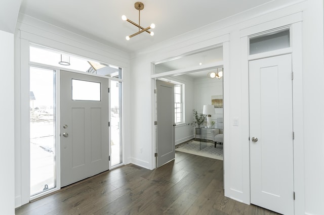 entrance foyer with a chandelier, dark wood-type flooring, baseboards, and a healthy amount of sunlight