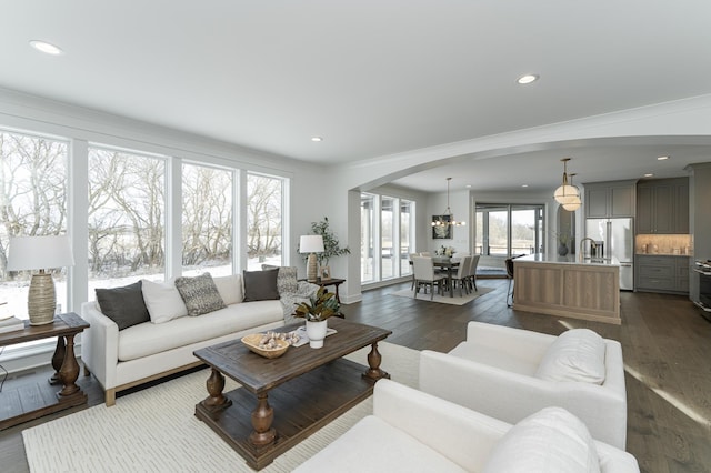 living room with dark wood-style floors, arched walkways, and recessed lighting