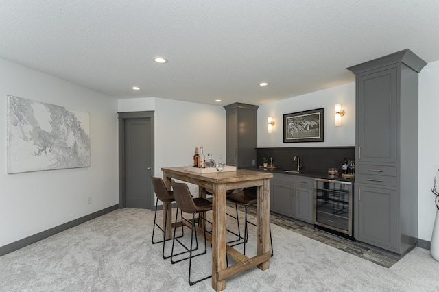 bar with wine cooler, indoor wet bar, recessed lighting, light carpet, and a sink