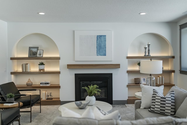 living room featuring a textured ceiling, a glass covered fireplace, and recessed lighting