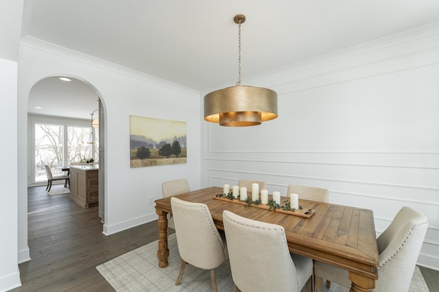 dining area with dark wood-style floors, arched walkways, ornamental molding, and baseboards