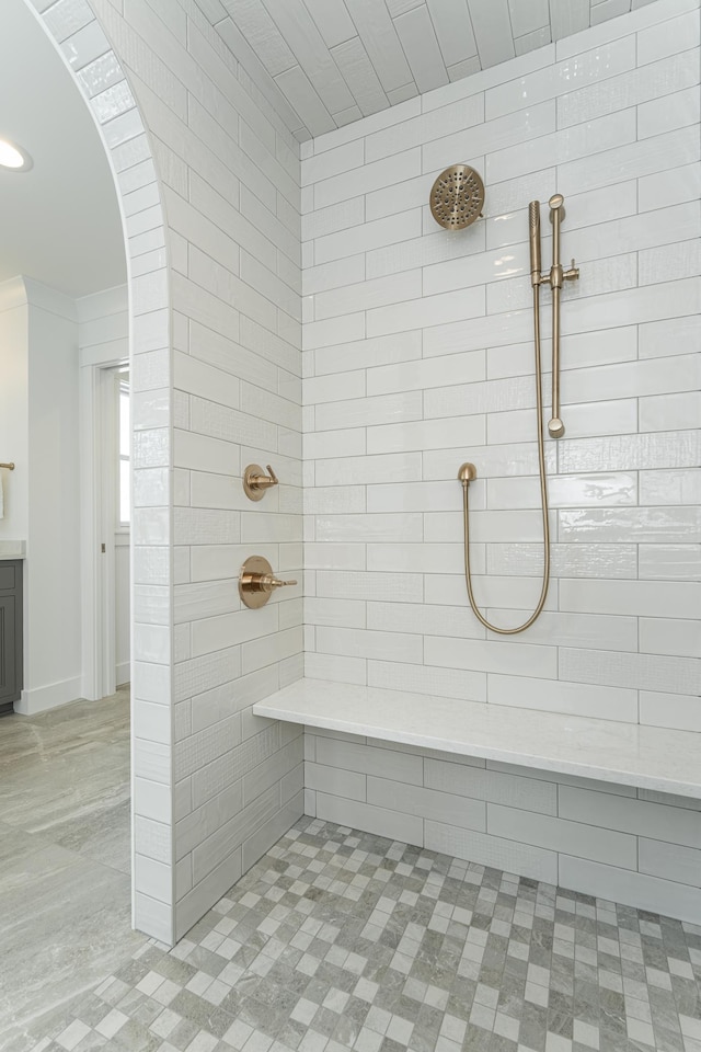 bathroom with ornamental molding and tiled shower