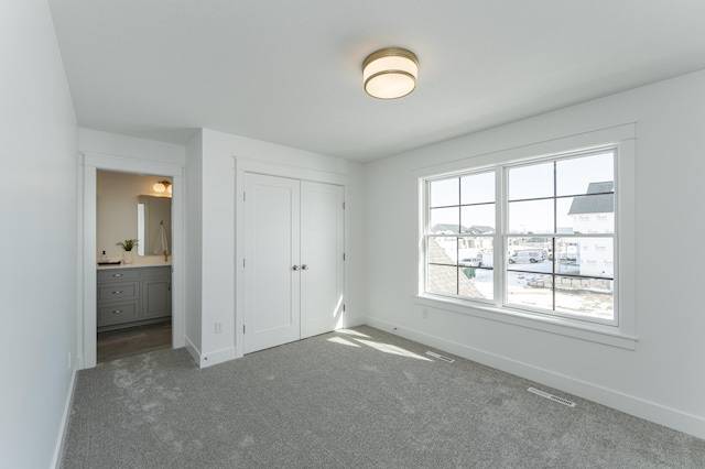 unfurnished bedroom featuring dark colored carpet, visible vents, and baseboards