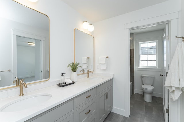 full bath featuring baseboards, a sink, toilet, and double vanity