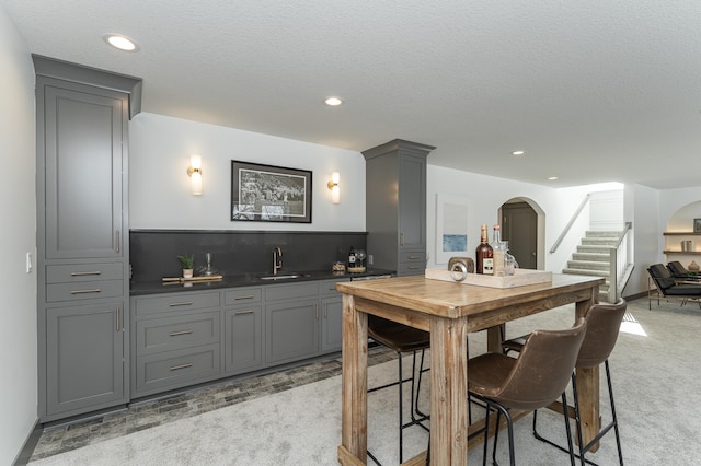 kitchen featuring recessed lighting, gray cabinets, a sink, and light colored carpet