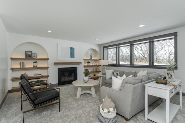 living room featuring a glass covered fireplace, baseboards, and recessed lighting