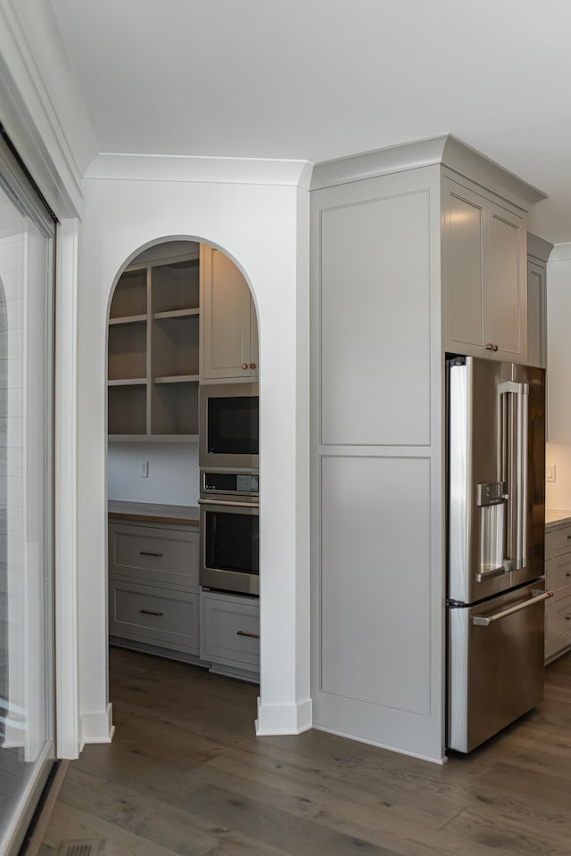 kitchen featuring appliances with stainless steel finishes, gray cabinets, dark wood-type flooring, and ornamental molding