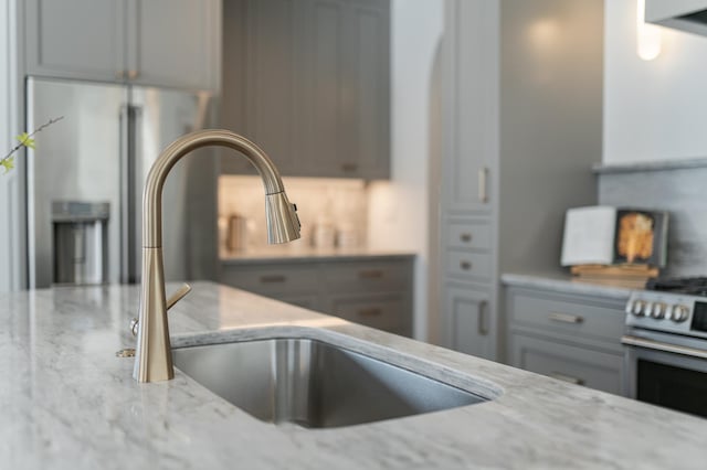 kitchen with light stone counters, stainless steel range with gas cooktop, and a sink