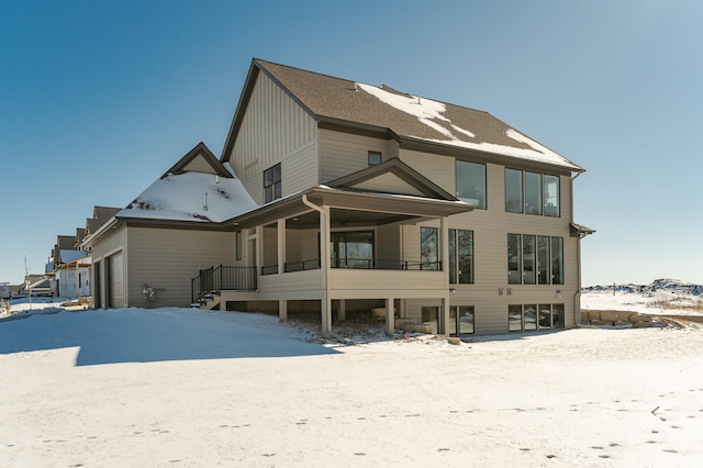 snow covered back of property with a garage and board and batten siding