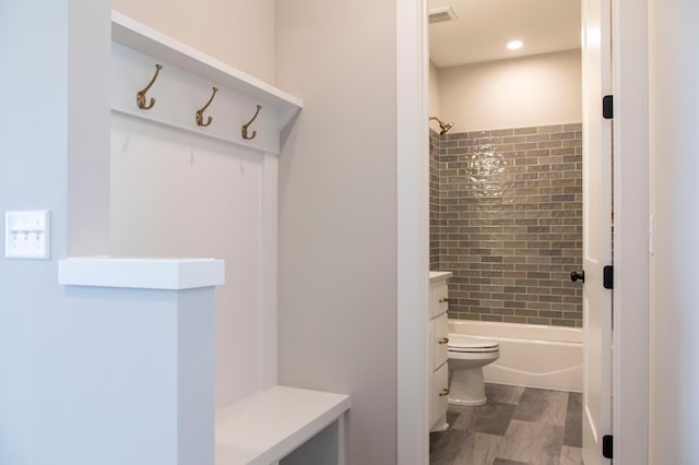 full bathroom with vanity, tiled shower / bath combo, and toilet