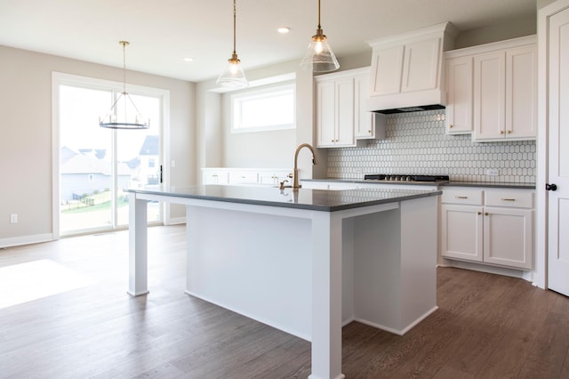 kitchen with white cabinetry, decorative light fixtures, dark hardwood / wood-style floors, and a kitchen island with sink