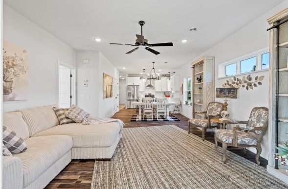 living room with dark hardwood / wood-style flooring and ceiling fan with notable chandelier