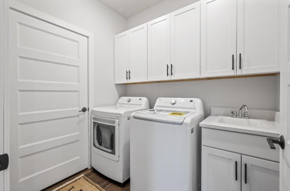 laundry room featuring washer and dryer, cabinets, sink, and dark wood-type flooring