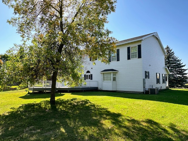 rear view of property featuring a lawn, central AC unit, and a wooden deck