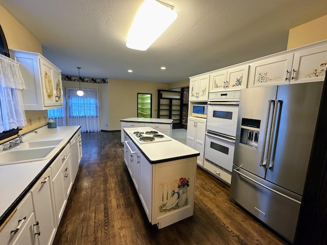 kitchen featuring sink, white cabinets, pendant lighting, and white appliances