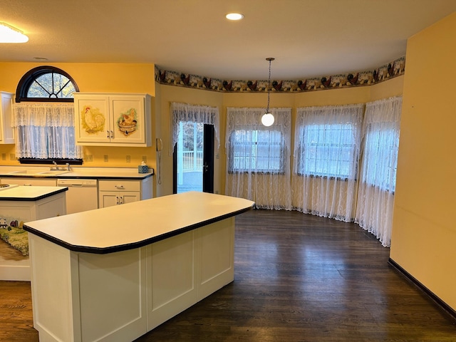 kitchen featuring white dishwasher, decorative light fixtures, a center island, dark hardwood / wood-style floors, and white cabinetry