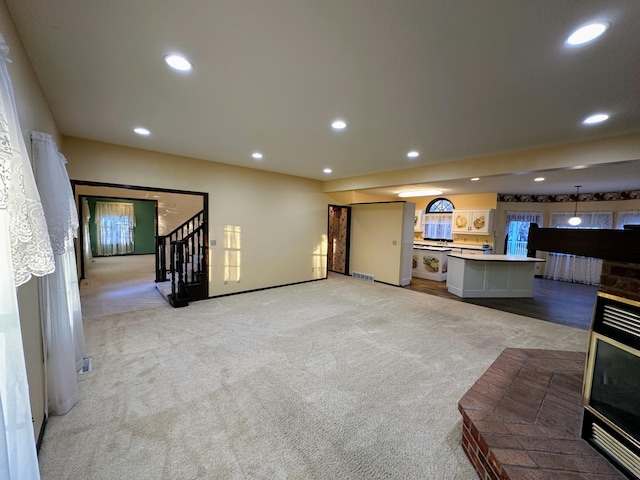 kitchen with decorative light fixtures, a kitchen island, and light carpet