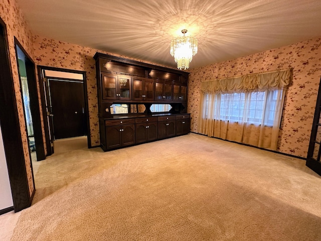 unfurnished living room featuring light colored carpet and an inviting chandelier